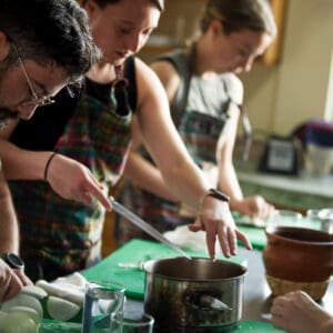 Group gathered in the kitchen chopping vegetables.