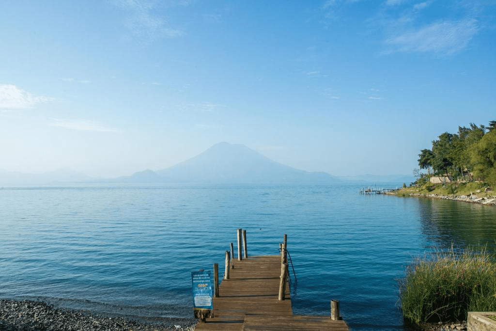 Quiet, blue lake with volcanoes in the distance.